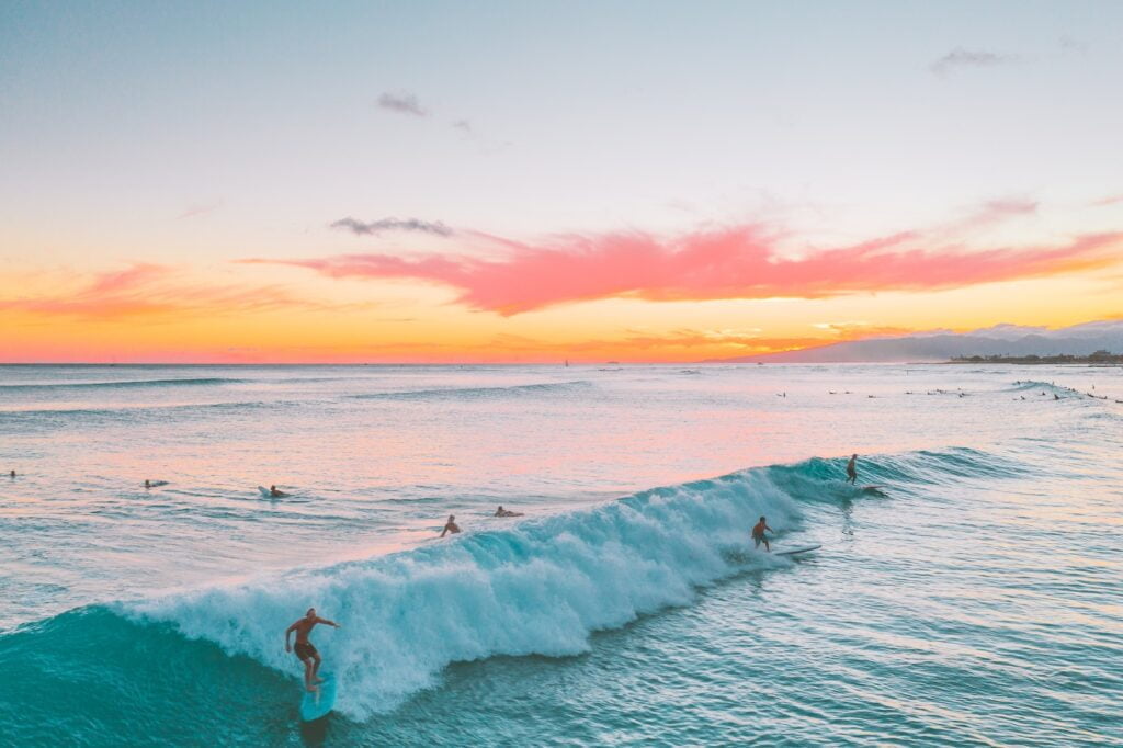 People surfing on sea waves during sunset