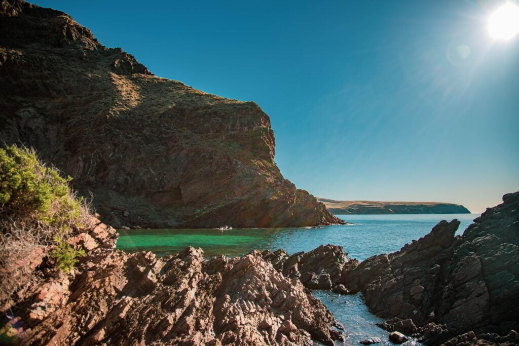 Brown rock formation on sea under blue sky during daytime