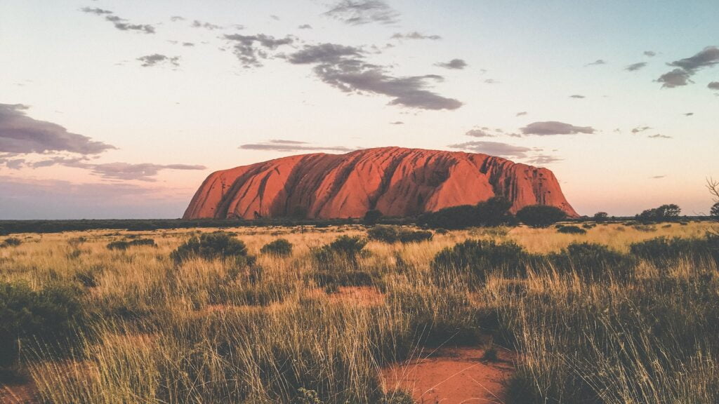 Find the best time to visit australia as a backpacker 13 Brown mountain under white clouds during daytime - uluru - uluru backpackers - best time of year to go backpacking in australia - darwin backpackers