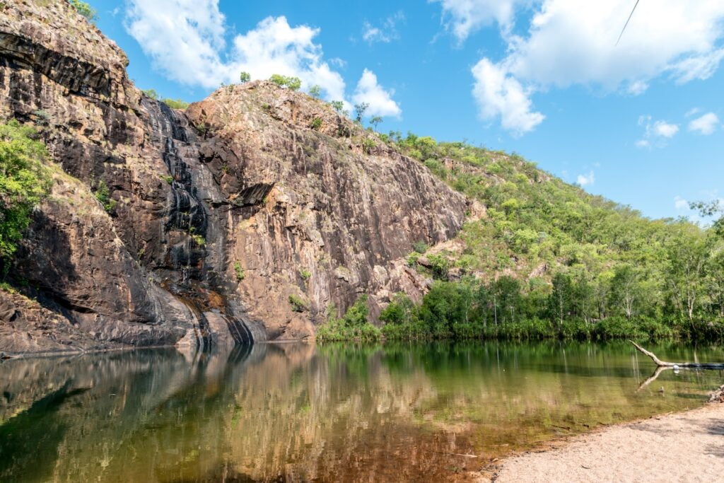 Find the best time to visit australia as a backpacker 9 Green and brown mountain beside river under blue sky during daytime - kakadu - uluru - northern territory backpackers - best time of year to go backpacking in australia - things to do in winter
