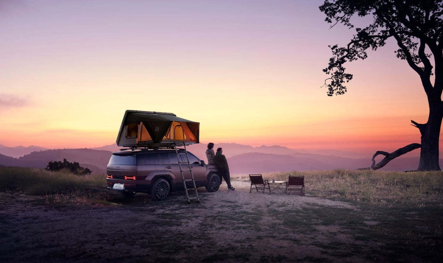 backpackers watching the sunset while leaning on the on a car while camping and hiking